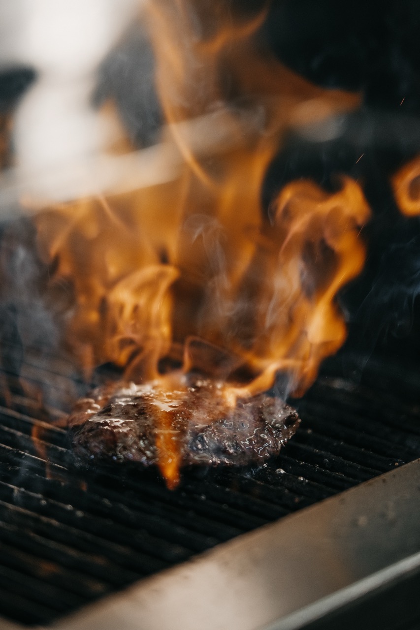 Burgerpatty auf dem Grill mit Flammen im Benner's Ingolstadt